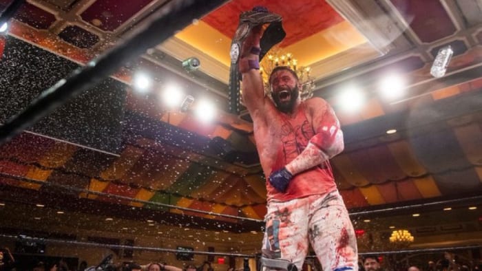 A bloody Matt Cardona celebrates after winning the GCW championship